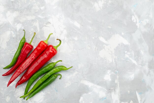 Top view colored spicy peppers green and red on grey