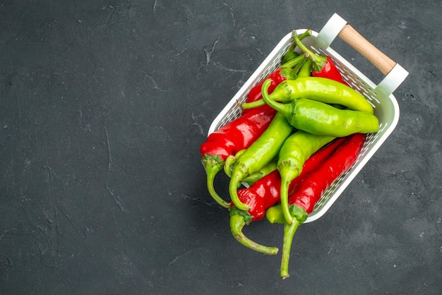 Free photo top view colored spicy peppers inside basket on dark background