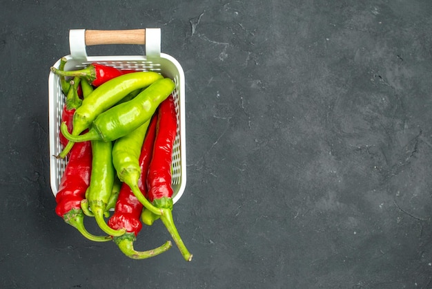 Free photo top view colored spicy peppers inside basket on dark background