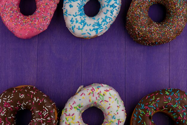 밝은 보라색 표면에 색깔의 달콤한 도넛의 상위 뷰