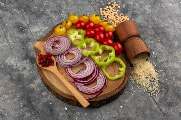 top view colored vegetables sliced and whole vegetables on the brown wooden desk on the grey