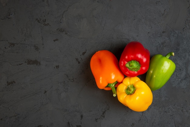 Top view of colorful bell peppers with copyspace on dark