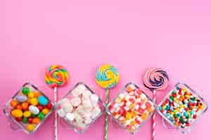 Free photo a top view colorful candies along with lollipops on pink desk