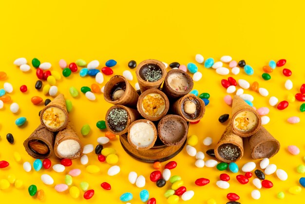 A top view colorful candies along with with horn ice-cream on yellow