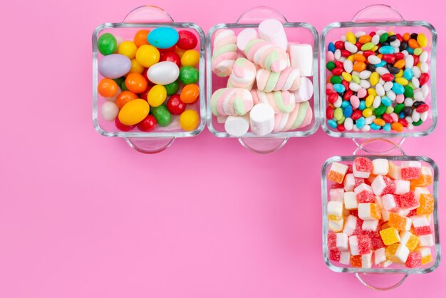 핑크 책상, 캔디 컬러 레인보우에 안경 안에 마멀레이드가있는 상위 뷰 다채로운 사탕