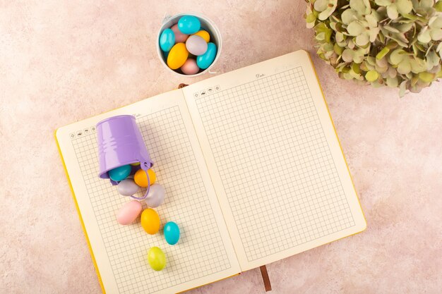 A top view colorful candies yummy with copybook on the pink desk candy bonbon color sweet