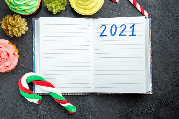 어두운 배경에 노트북 크리스마스 사탕과 장식품에 쓰여진 상위 뷰 다채로운 컵 케이크
