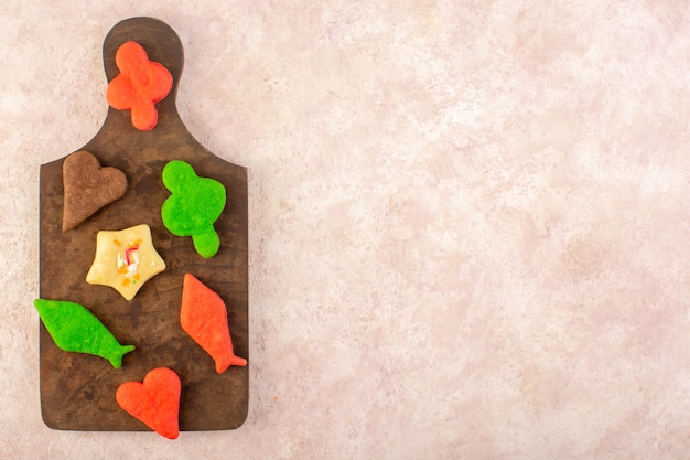 Top view of colorful delicious cookies different formed on the brown wooden desk