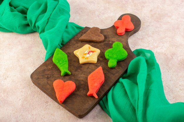 Top view of colorful delicious cookies different formed on the brown wooden desk