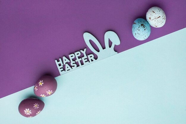 Top view of colorful easter eggs with bunny ears and greeting