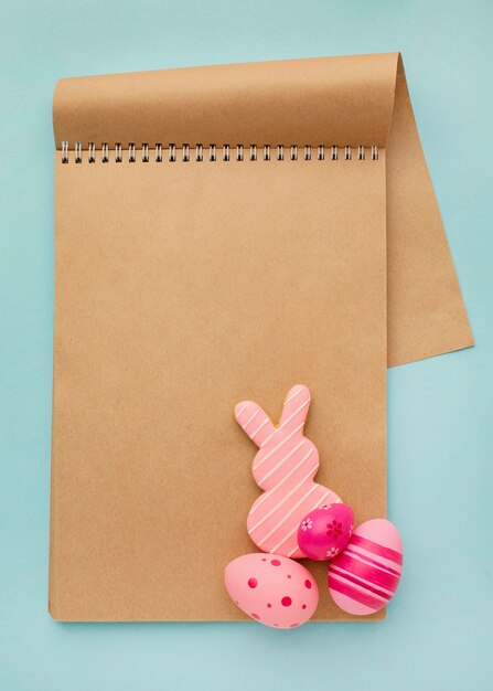 Top view of colorful easter eggs with notebook and bunny