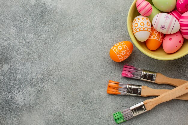 Top view of colorful easter eggs with paint brushes and copy space