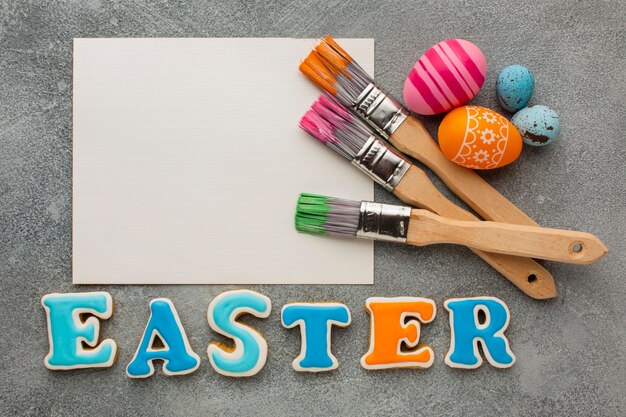 Top view of colorful easter eggs with paint brushes and paper