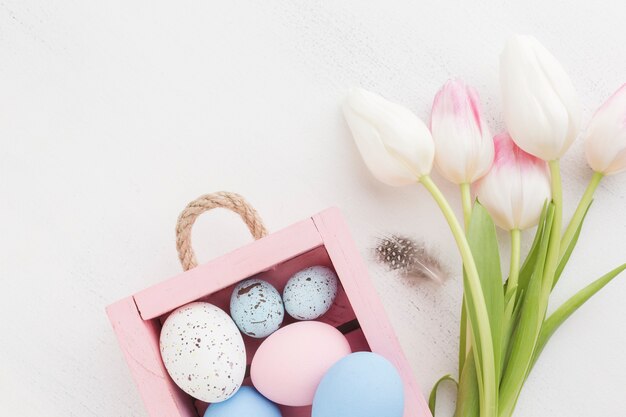 Top view of colorful easter eggs with pretty tulips