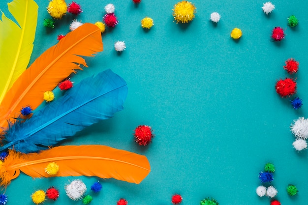 Top view of colorful feathers and pom-poms