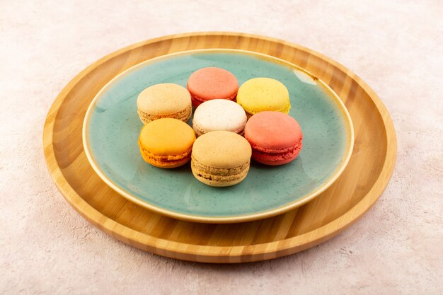 A top view colorful french macarons delicious inside round plate on the pink desk biscuit cake sugar sweet