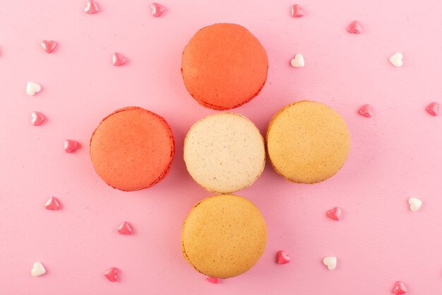 A top view colorful french macarons round formed delicious on the pink desk cake biscuit sugar sweet