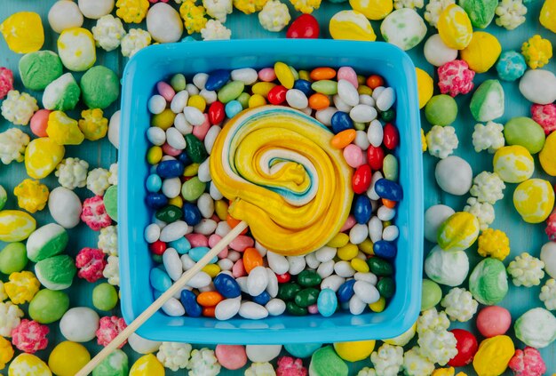 Top view of  colorful lollipop on candies in multi-colored glaze background