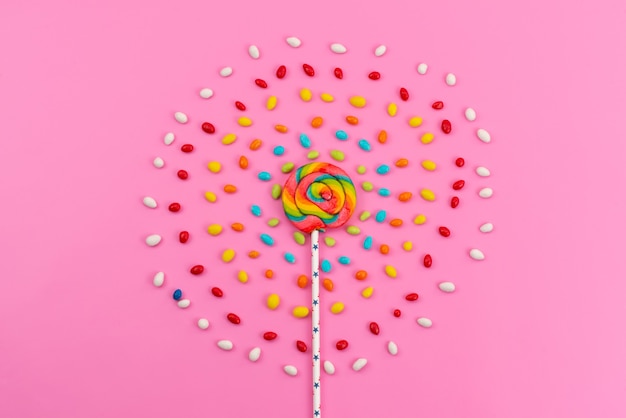 A top view colorful lollipop with colored candies on pink, candy color sugar rainbow