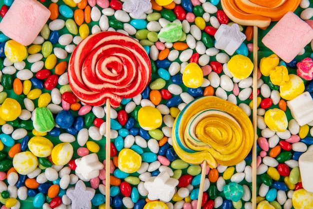 Top view of  colorful lollipops on candies in multi-colored glaze background