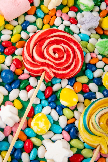 Top view of  colorful lollipops on candies in multi-colored glaze background