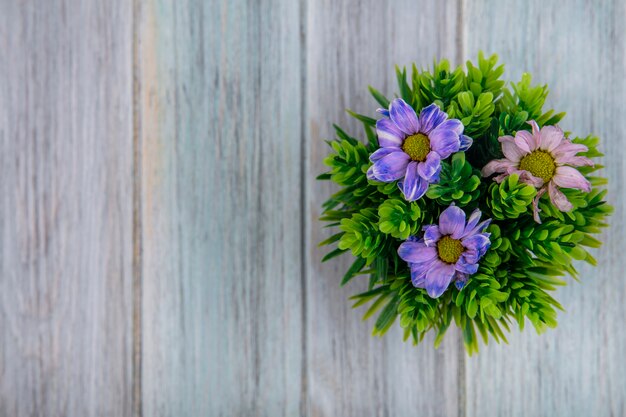 Top view of colorful lovely daisy flowers on a gray wooden background with copy space