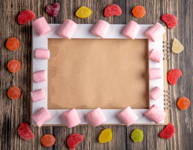 소박한에 빈 그림 프레임과 마멀레이드 사탕에 배열하는 다채로운 마쉬 멜로우의 상위 뷰