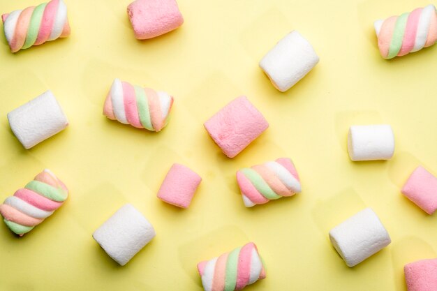 Top view of colorful marshmallow scattered on yellow