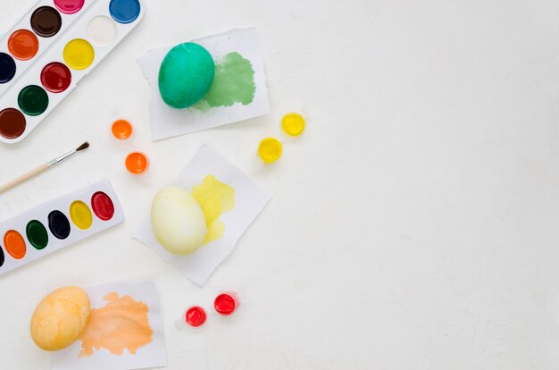 Top view of colorful paint palettes and easter eggs