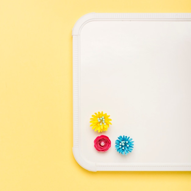 Top view of colorful paper flowers on whiteboard