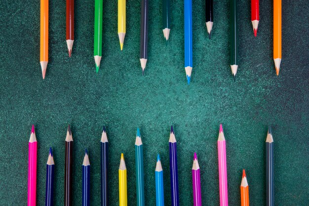 Top view colorful pencils on a green background