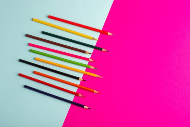 青とピンクの机の色の描画アートペイントに並ぶ上面図カラフルな鉛筆