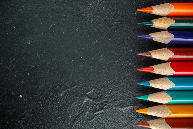 Top view colorful pencils lined on dark background