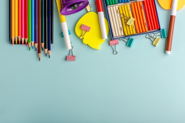 Top view colorful plasticines with colored pencils on the blue desk color school kids children book