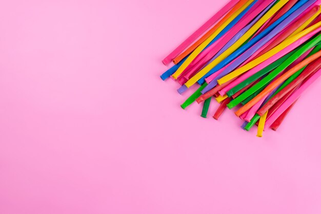 A top view colorful sticks long and straw looking like on pink, color photo composition