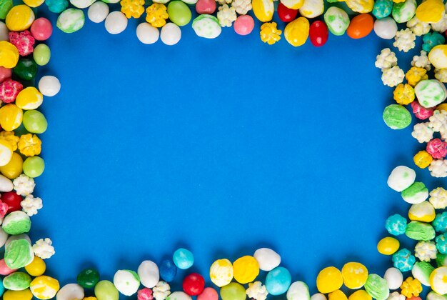 Top view of colorful sweet sugar candies on blue wooden background with copy space