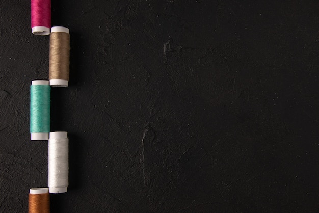 Top view of colorful threads on dark wall