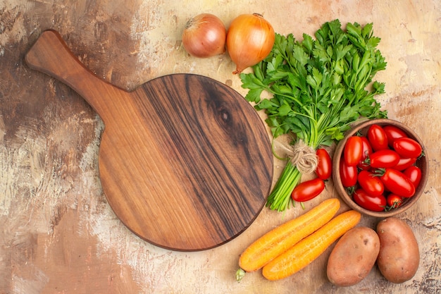 Top view colorful vegetables and a cutting board for preparation of fresh salad on a wooden background with copy space