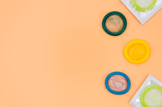 Top view colourful condoms on orange background 