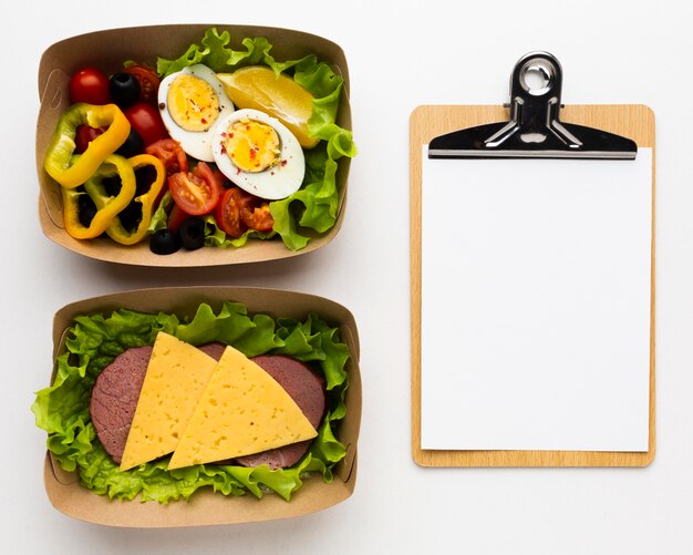 Top view composition of different meals with empty clipboard