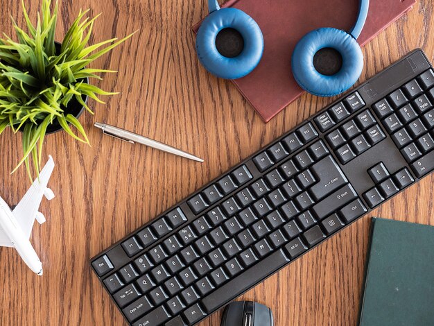 Top view concept image of businessman on wooden des, pot of grass, headphones, books