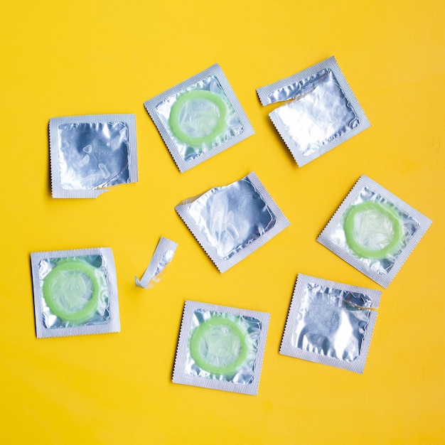 Top view condoms wrappers on yellow background