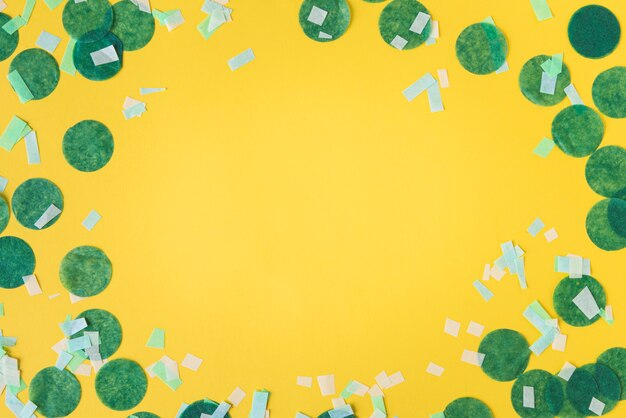 Top view of confetti frame on yellow background with copy space