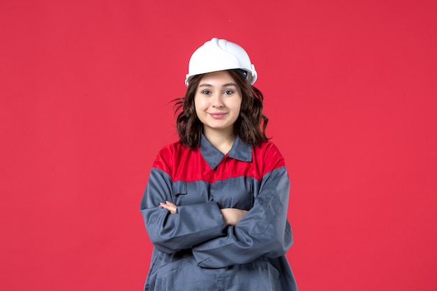 Top view of confident female builder in uniform with hard hat on isolated red background