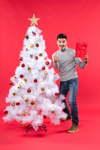 Top view of confident young man standing near the decorated white New Year tree