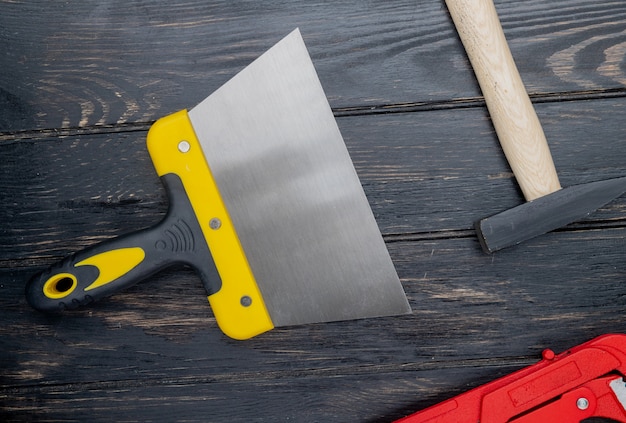 Foto gratuita vista superiore degli strumenti della costruzione come coltello del mastice e martello del mattone su fondo di legno