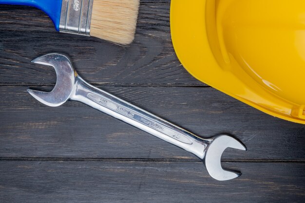 Top view of construction tools as safety helmet paint brush and open-end wrench on white background