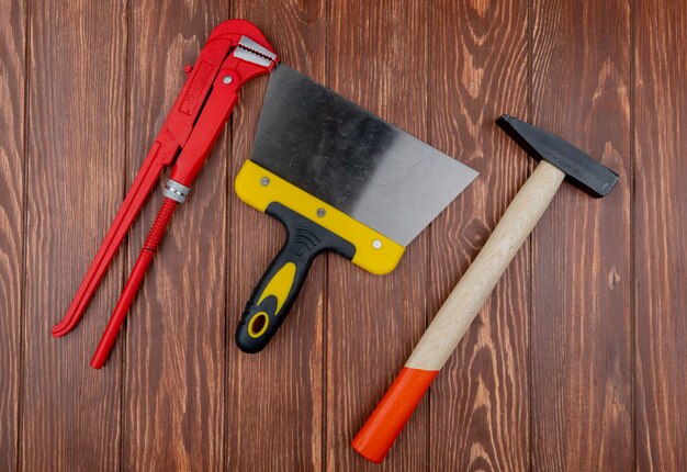 Top view of construction tools as wrench putty knife and brick hammer on wooden background