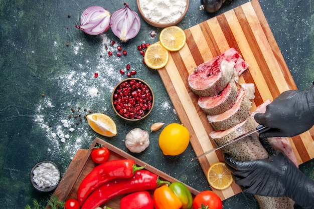 Free photo top view cook cutting raw fish on cutting board vegetables on wood board on table