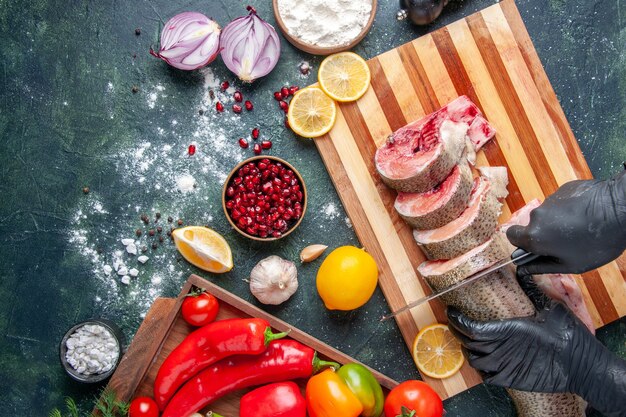 Top view cook cutting raw fish on cutting board vegetables on wood board on table